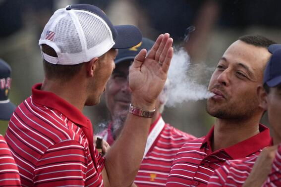 FILE - Xander Schauffele blows smoke toward Jordan Spieth after the USA team defeated the International team in a singles match at the Presidents Cup golf tournament at the Quail Hollow Club, Sunday, Sept. 25, 2022, in Charlotte, N.C. Schauffele ended three years without winning by winning three times this year. (AP Photo/Chris Carlson, File)