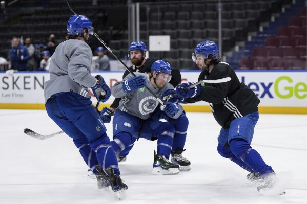 Vancouver Canucks' Quinn Hughes, right, and Filip Hronek, back center, defend against Brock Boeser, center, and J.T. Miller during practice ahead of Game 1 of their NHL hockey Stanley Cup second-round playoff series against the Edmonton Oilers, in Vancouver, British Columbia, Tuesday, May 7, 2024. (Darryl Dyck/The Canadian Press via AP)