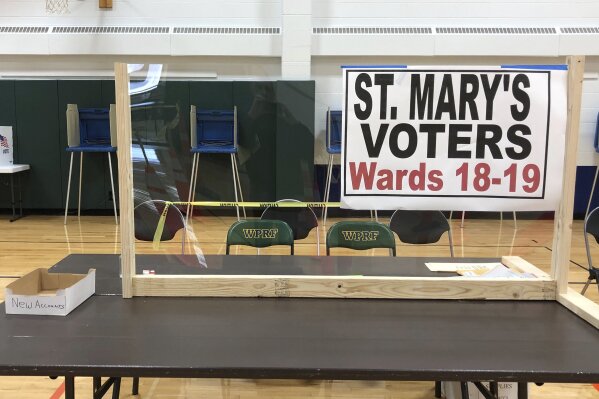 This April 6, 2020 photo provided by Scott Trindl shows one of the tables, fitted with protective plexiglass, at the sole polling location for city of Waukesha, Wis., residents. Wisconsin Gov. Tony Evers on Monday, April 6, 2020 moved to postpone the state's presidential primary for two months because of the coronavirus pandemic, prompting a court challenge and adding to confusion about whether voters will be able to head to the polls on Tuesday. (Scott Trindl via AP)