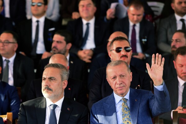 Turkish President Recep Tayyip Erdogan, right, waves during a military parade, in the Turkish occupied area of the divided capital Nicosia, Cyprus, Thursday, July 20, 2023. Erdogan is in Cyprus for the 49th anniversary celebrations of the Turkish invasion on July 20, 1974. (AP Photo/Nedim Enginsoy)