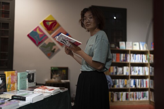 Lu Sirui looks up while reading the book "Misogyny" written by Chizuko Ueno, in a bookstore specialising in feminist literature in Beijing on Thursday, July 27, 2023. Like a growing number of Chinese women, Lu was inspired by this book in 2022 and became a feminist. From time to time, she would go back to Ueno's books to think about gender-based issues. in Beijing, (AP Photo/Ng Han Guan)