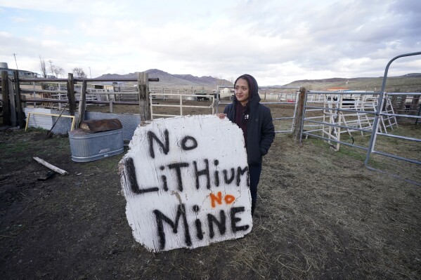 FILE - Daranda Hinkey, a Fort McDermitt Paiute and Shoshone tribe member, holds a large hand-painted sign that reads, "No Lithium No Mine," at her home on the Fort McDermitt Indian Reservation, April 24, 2023, near McDermitt, Nev. A federal judge in Nevada has dealt another legal setback to tribes trying to halt construction of a huge lithium mine they say is near the sacred site of an 1865 massacre along the Oregon border. (AP Photo/Rick Bowmer, File)