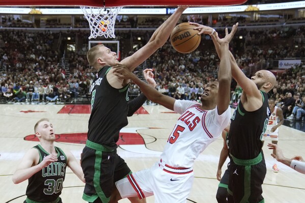 Boston Celtics' Derrick White, right, blocks the shot of Chicago Bulls' Julian Phillips, second from right, as Celtics' Kristaps Porzingis, second from left, also defends during the first half of an NBA basketball game Thursday, Feb. 22, 2024, in Chicago. (AP Photo/Charles Rex Arbogast)