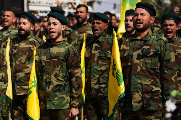 Hezbollah fighters shout slogans as they attend the funeral procession of Hezbollah fighter, Bilal Nemr Rmeiti, who was killed by Israeli shelling, during his funeral procession in Majadel village, south Lebanon, Sunday, Oct. 22, 2023. (AP Photo/Hassan Ammar)
