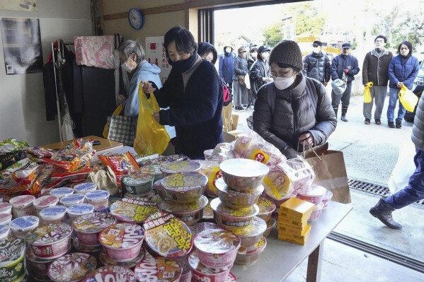 Las personas afectadas por un fuerte terremoto reciben alimentos en Wajima, prefectura de Ishikawa, Japón, el viernes 5 de enero de 2024. El terremoto del lunes destruyó casas, caminos retorcidos y llenos de cicatrices y esparció botes como si fueran juguetes en el agua, y provocó advertencias de tsunami.  (Noticias de Kyodo vía Associated Press)