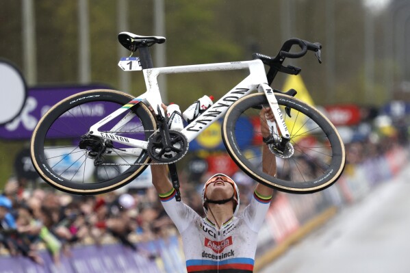 FILE - Netherland's Mathieu van der Poel holds his bike up at the finish line after taking first place in the Tour of Flanders in Oudenaarde, Belgium on March 31, 2024. World champion Mathieu van der Poel will focus on the Olympic road race at the Paris Games this summer after the Tour de France, skipping mountain biking. The versatile Dutch racer said on Wednesday that combining the Tour and the Olympic road race is “the most logical” choice. (Ǻ Photo/Geert Vanden Wijngaert, File)