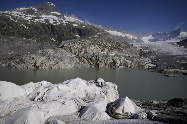Workers prepare sheets to cover the Rhone Glacier near Goms, Switzerland, June 10, 2025. (AP Photo/Matthias Schrader)