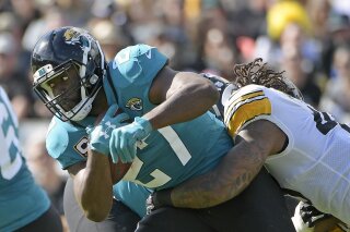 FILE - In this Nov. 18, 2018, file photo, Jacksonville Jaguars running back Leonard Fournette, left, runs for yardage as he is stopped by Pittsburgh Steelers outside linebacker Bud Dupree, right, during the first half of an NFL football game in Jacksonville, Fla. A person familiar with the situation says the Jacksonville Jaguars have notified running back Leonard Fournette that his suspension late last month voided the remaining guarantees in his four-year rookie contract. The person spoke to The Associated Press on the condition of anonymity Sunday night, Dec. 30, 2018 .(AP Photo/Phelan M. Ebenhack, File)