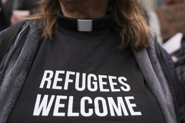 La pastora Jennifer Castle, con un mensaje a favor de los refugiados en su ropa, participa en un mitin en el exterior de la Corte de Distrito de Estados Unidos luego de que un juez federal bloqueó una iniciativa de Donald Trump para suspender el programa de admisiones de refugiados del país, el 25 de febrero de 2025 en Seattle. (AP Foto/Ryan Sun)