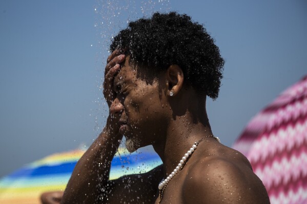 FILE - A man cools off in a shower at Ipanema beach, Rio de Janeiro, Brazil, Sept. 24, 2023. After a summer of record-smashing heat, warming somehow got even worse in September as Earth set a new mark for how far above normal temperatures were, the European climate agency reported Thursday, Oct. 5. (AP Photo/Bruna Prado, File)