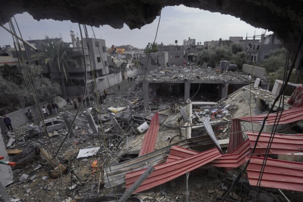 Palestinians inspect the rubble of a building of the Al Nawasrah family destroyed in an Israeli strike in Maghazi refugee camp, central Gaza Strip, Monday, Dec. 25, 2023. (AP Photo/Adel Hana)