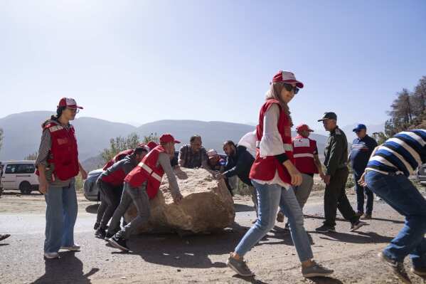 Moroccan Red Crescent workers help remove large stones which fell on roads during an earthquake, on the way to affected villages in the Middle Atlas mountain, near Marrakech, Morocco, Saturday, Sept. 9, 2023. (AP Photo/Mosa'ab Elshamy)