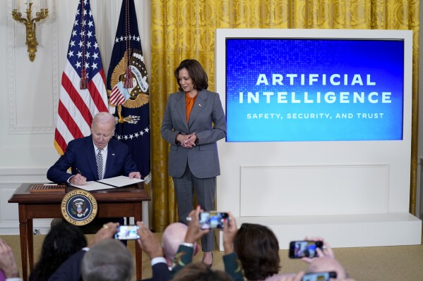 FILE - President Joe Biden signs an executive on artificial intelligence in the East Room of the White House, Oct. 30, 2023, in Washington. Vice President Kamala Harris looks on at right. The White House said Wednesday, Feb. 21, 2024, that it is seeking public comment on the risks and benefits of having an AI system's key components publicly available for anyone to use and modify. (APPhoto/Evan Vucci, File)