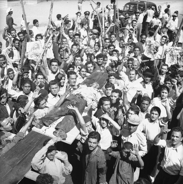 FILE - The body of a man killed in a pro-Shah riot which swept through Tehran is carried aloft by demonstrators on Aug. 19, 1953. In August 1953, a CIA-backed coup toppled Iran's prime minister, cementing the rule of Shah Mohammad Reza Pahlavi for over 25 years before the 1979 Islamic Revolution. (AP Photo/Aziz Rashki, File)