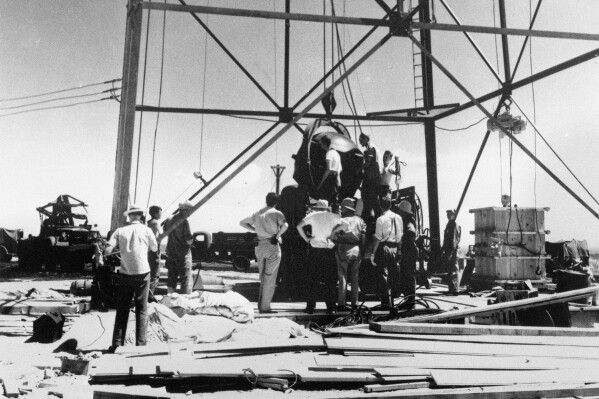 FILE - Scientists and other workers rig the world's first atomic bomb to raise it up onto a 100-foot tower at the Trinity Test Site near Alamogordo, N.M. The New Mexico site where the world’s first atomic bomb was detonated is expecting thousands of visitors Saturday due to the popularity of the movie, "Oppenheimer." Trinity Site, a designated National Historic Landmark, only opens to the public twice a year. (AP Photo/File )