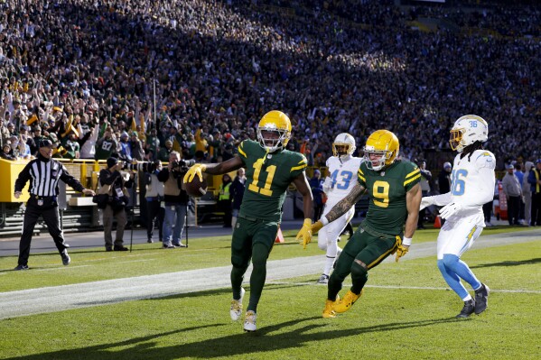 Green Bay Packers wide receiver Jayden Reed (11) celebrates his first half touchdown with wide receiver Christian Watson (9) as Los Angeles Chargers cornerback Michael Davis (43)and cornerback Ja'Sir Taylor (36) look on during an NFL football game, Sunday, Nov. 19, 2023, in Green Bay, Wis. (AP Photo/Matt Ludtke)