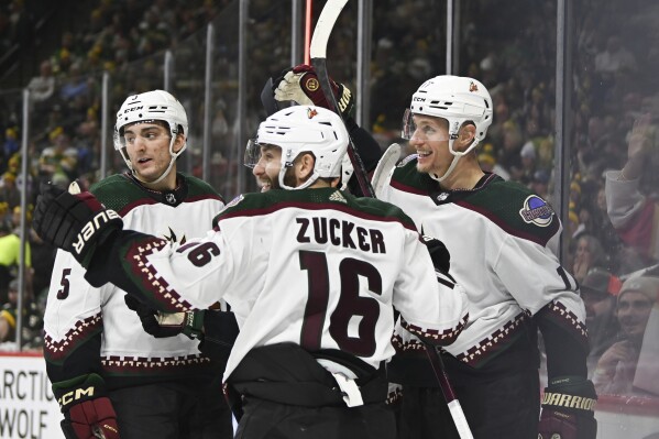 Arizona Coyotes center Nick Bjugstad, right, celebrates with right wing Jason Zucker (16) and defenseman Michael Kesselring (5) after scoring his third goal of an NHL hockey game against the Minnesota Wild, during the second period, Saturday, Jan. 13, 2024, in St. Paul, Minn. (AP Photo/Craig Lassig)