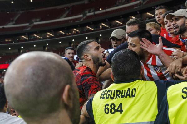 Atletico's Mario Hermoso, centre speaks with angry home fans after Villarreal's Gerard Moreno celebrated scoring by sticking his tongue out and touching his ears provoking anger from Atletico players and fans during a Spanish La Liga soccer match between Atletico Madrid and Villarreal at the Metropolitano stadium in Madrid, Spain, Sunday, Aug. 21, 2022. (AP Photo/Pablo Garcia)