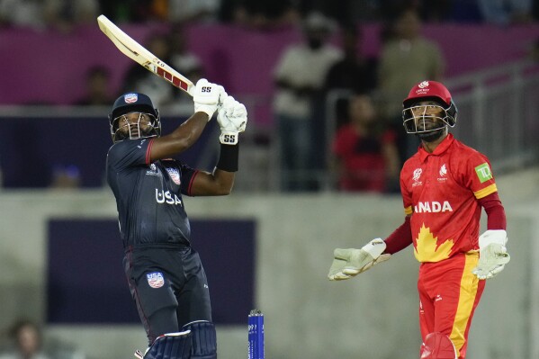 United States' Aaron Jones, hits a six as Canada's Shreyas Movva watches during the men's T20 World Cup cricket match between the United States and Canada at Grand Prairie Stadium, in Grand Prairie, Texas, Saturday, June 1, 2024. (AP Photo/Julio Cortez)
