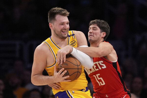 Houston Rockets guard Reed Sheppard, right, reaches in on Los Angeles Lakers guard Luka Doncic during the first half of an NBA basketball game Friday, April 11, 2025, in Los Angeles. (AP Photo/Mark J. Terrill)