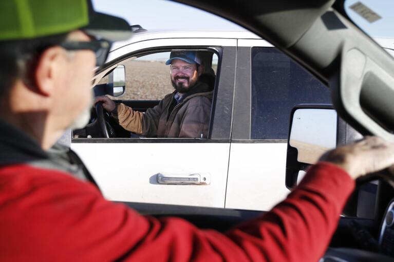 Tim Black, left, stops to talk to his son, Tyler, on their farm in Muleshoe, Texas, on Monday, April 19, 2021. The longtime corn farmers now raise cattle and have planted some land in wheat and native grasses because the Ogallala Aquifer, used to irrigate crops, is drying up. (AP Photo/Mark Rogers)