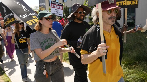 Marc Maron, right, Hannah Einbinder, from second left, and Debby Ryan walk on a picket line outside Netflix studios on Friday, July 21, 2023, in Los Angeles. The actors strike comes more than two months after screenwriters began striking in their bid to get better pay and working conditions. (AP Photo/Chris Pizzello)