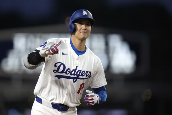 Los Angeles Dodgers' Shohei Ohtani gestures as he round third after hitting a solo home run during the first inning of a baseball game against the San Diego Padres Friday, April 12, 2024, in Los Angeles. (AP Photo/Mark J. Terrill)