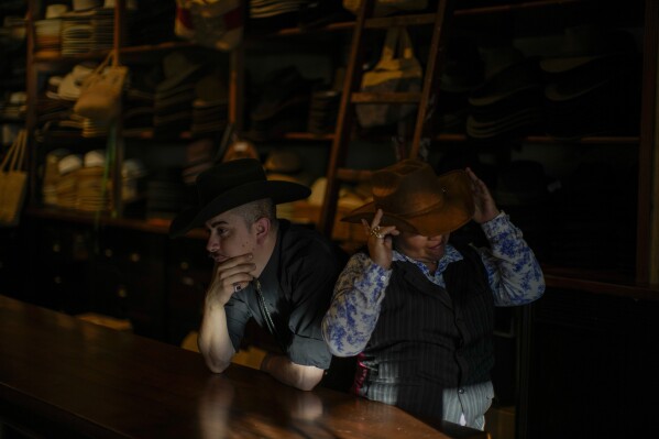 Employees wait for customers to arrive at the “Donde Golpea el Monito” hat shop and museum, in Santiago, Chile, Thursday, April 3, 2025, that preserves a hat-making tradition dating back to 1915. (AP Photo/Esteban Felix)