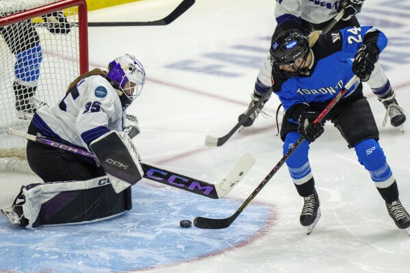 Minnesota goaltender Maddie Rooney (35) makes a save against Toronto's Natalie Spooner (24) during first-period PWHL hockey playoff action in Toronto, Friday, May 10, 2024. (Frank Gunn/The Canadian Press via AP)
