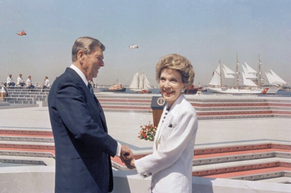FILE - President Ronald Reagan and first lady Nancy Reagan hold hands as they watch the start of Op Sail from Governor's Island in New York Harbor on July 4, 1986. (AP Photo/Ira Schwarz, File)