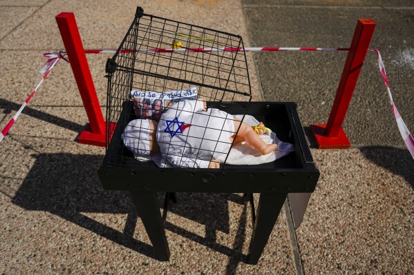 An installation of a baby and a pillow with the Hebrew writing "These are all our children" and photos of children missing and held captive in Gaza, in Tel Aviv, Israel, Tuesday, Nov. 21, 2023. (AP Photo/Ariel Schalit)