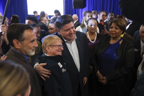 Illinois Gov. JB Pritzker, center, poses for a photo during the McIntyre-Shaheen 100 Club Dinner, Sunday April 27, 2025, in Manchester, N.H. (AP Photo/Reba Saldanha)