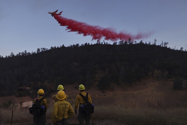 U,S. Forest Service firefighters from Stonyford, Calif., from left, Vivian Perez, Emma Nieforth, Jonny Connelly and Nick Bonnie watch as a BAe-146 air tanker is used to go indirect on the Ridge Fire, as a secondary contingency line, July 20, 2024, east of Clearlake, Calif. (Kent Porter/The Press Democrat via AP, File)
