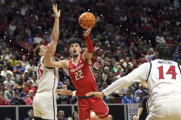 New Mexico forward Mustapha Amzil (22) shoots between San Diego State forward Elijah Saunders (25) and guard Reese Waters (14) during the first half of an NCAA college basketball championship game at the Mountain West Conference tournament Saturday, March 16, 2024, in Las Vegas. (AP Photo/Steve Marcus)