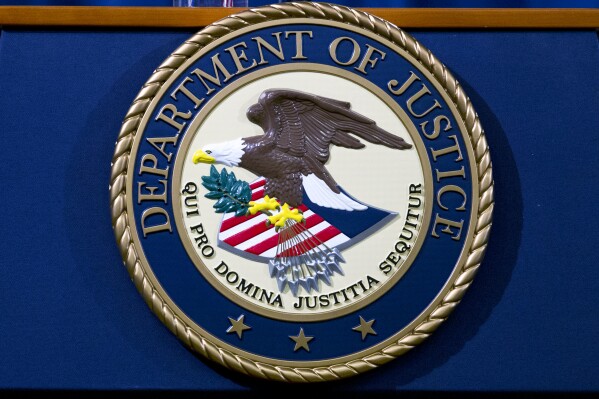 FILE - The Department of Justice seal is seen in Washington, Nov. 28, 2018. The Justice Department says a contractor for the U.S. government who is originally from Ethiopia has been arrested on espionage charges, accused of providing a foreign country classified information that he downloaded and printed from his work computer system. (AP Photo/Jose Luis Magana, File)