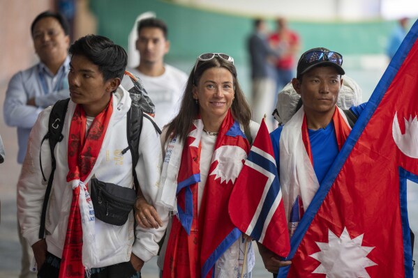 Norwegian woman mountain climber Kristin Harila, center and her Nepali Sherpa guide Tenjen Sherpa, right, who on Thursday set a new record by scaling the world's 14 highest peaks in 92 days arrive at the airport in Kathmandu, Nepal, Saturday, Aug.5, 2023. (AP Photo/Niranjan Shrestha)