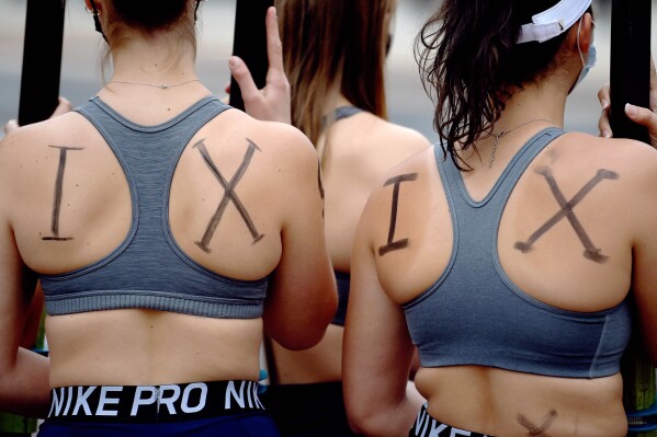 FILE - Members of the UConn women's rowing team rally about being cut by the university after the season, in Storrs, Conn., April 19, 2021. The looming athlete pay system that will upend the traditional college sports model and still-to-be-determined details about how millions of dollars will be distributed are certain to bring questions about gender equity. Of special interest will be whether schools must comply with Title IX, the federal law that prohibits sex discrimination in any school or education program that receives federal funds. (Brad Horrigan/Hartford Courant via AP, File)