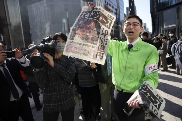 A staff distributes an extra edition of the Yomiuri Shimbun newspaper reporting on Shohei Ohtani to move to the Los Angeles Dodgers Sunday, Dec. 10, 2023, in Tokyo. Ohtani agreed to a record $700 million, 10-year contract with the Los Angeles Dodgers. (AP Photo/Eugene Hoshiko)