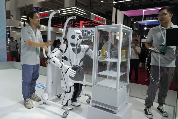 A panda shaped robot demonstrates its ability to grab a can of soda at the annual World Robot Conference at the Beijing Etrong International Exhibition and Convention Center in Beijing, Wednesday, Aug. 16, 2023. (AP Photo/Ng Han Guan)