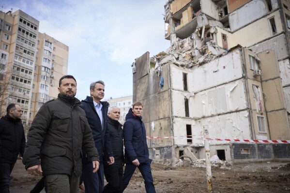 In this photo provided by the Ukrainian Presidential Press Office, Ukrainian President Volodymyr Zelenskyy, second from left, and Greece's Prime Minister Kyriakos Mitsotakis, third from left, walk in a residential area damaged by Russian attack in Odesa, Ukraine, Wednesday, March 6, 2024. The sound of a large explosion reverberated around the Ukrainian port of Odesa as President Volodymyr Zelenskyy and Greece's prime minister ended a tour of the war-ravaged southern city Wednesday. (Ukrainian Presidential Press Office via AP)