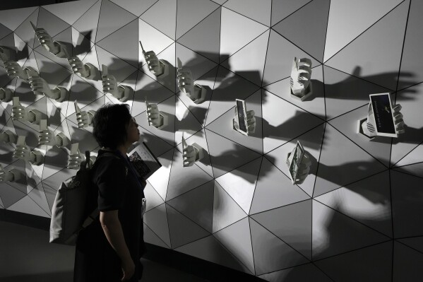 People look at artwork at the COP28 U.N. Climate Summit, Dec. 3, 2023, in Dubai, United Arab Emirates. (AP Photo/Peter Dejong)