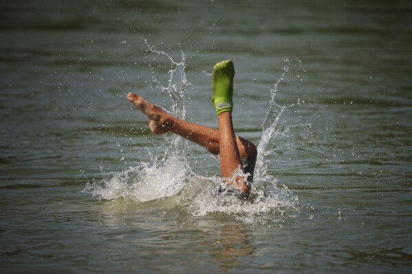 A boy shows off his swimming skills while cooling off in the river Arges, outside Bucharest, Romania, Wednesday, July 12, 2023. (AP Photo/Andreea Alexandru)