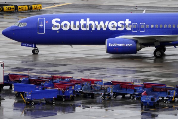 FILE - A Southwest Airlines jet passes luggage carts as it arrives, Dec. 28, 2022, at Sky Harbor International Airport in Phoenix. A federal judge has set off a debate among legal scholars by ordering lawyers for Southwest Airlines to undergo "religious-liberty training" by a conservative Christian legal group. (AP Photo/Matt York, File)