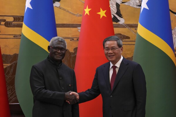 Visiting Solomon Islands Prime Minister Manasseh Sogavare, left, shakes hands with his Chinese counterpart Li Qiang after they witnessed signing on agreement for both countries at the Great Hall of the People in Beijing, Monday, July 10, 2023. (AP Photo/Andy Wong, Pool)
