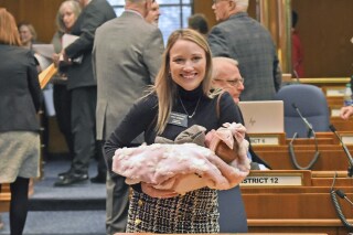 FILE - Rep. Emily O'Brien R-Grand Forks carries daughter Jolene Green, 3 weeks, into the House chamber, Dec. 6, 2022, in Bismarck, N.D. Last year, the state representative helped persuade her colleagues to approve $66 million in child care spending proposed by Gov. Doug Burnum, a Republican. O'Brien argued it could help the state's workforce shortage by helping more parents go to work. (Tom Stromme/The Bismarck Tribune via AP)