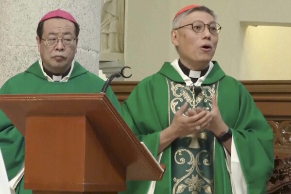 In this photo taken from video and released on Nov. 17, 2023 by Hong Kong Catholic Diocese, Beijing Bishop Joseph Li Shan, at left, and Hong Kong Bishop and Cardinal Stephen Chow during a ceremony at Hong Kong's Cathedral of the Immaculate Conception. Hong Kong's newly appointed Roman Catholic cardinal said he dreamed of bishops and faithfuls from different parts of greater China praying together one day during a historic visit by the head of the Chinese Catholic church, a publication affiliated with the city's diocese reported Friday. (Hong Kong Catholic Diocese via AP)