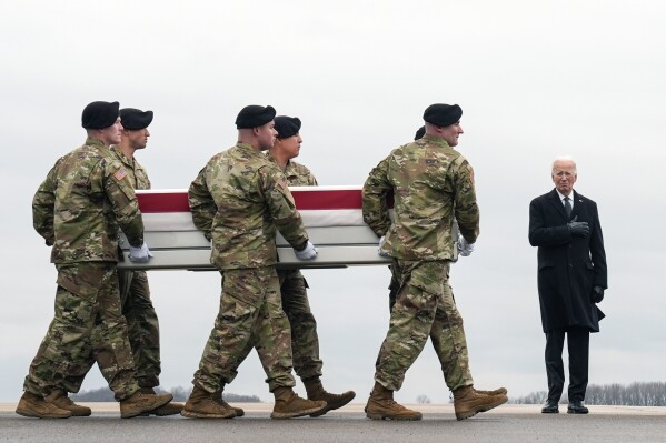 President Joe Biden, right, stands as an Army carry team moves the transfer case containing the remains of U.S. Army Sgt. Kennedy Ladon Sanders, 24, of Waycross, Ga., at Dover Air Force Base, Del., Friday, Feb. 2, 2024. Sanders was killed in a drone attack in Jordan on Jan. 28. (AP Photo/Matt Rourke)