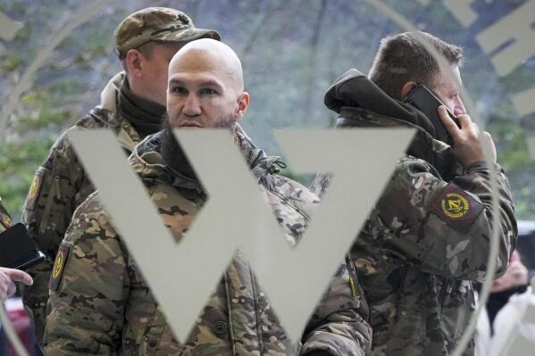 FILE - Visitors wearing military camouflage stand at the entrance of the 'PMC Wagner Centre', which is associated with businessman and founder of the Wagner private military group Yevgeny Prigozhin, during the official opening of the office block during National Unity Day, in St. Petersburg, Russia, on Nov. 4, 2022. Russia's Wagner Group, a private military company led by Yevgeny Prigozhin, a rogue millionaire with longtime links to Russia's President Vladimir Putin, has played an increasingly visible role in the fighting in Ukraine. (AP Photo, File)