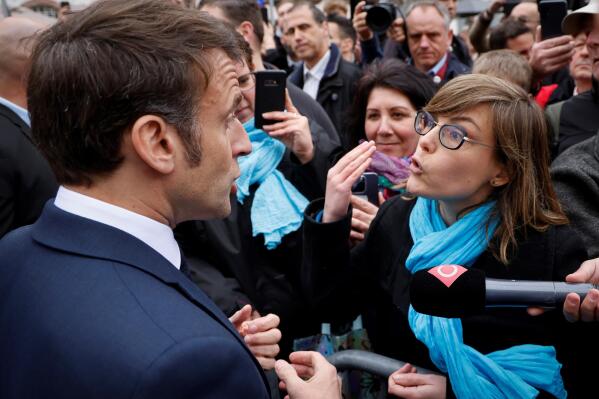 French President Emmanuel Macron argues with a person opposed to the pension reform, in Selestat, eastern France, Wednesday, April 19, 2023. French President Emmanuel Macron said Monday April 17, 2023 that he heard people's anger over raising the retirement age from 62 to 64, but insisted that it was needed to keep the pension system afloat as the population ages. Emmanuel Macron is trying to repair the damage done to his public image and politics by forcing the pension plan through parliament last month. (Ludovic Marin, Pool via AP)