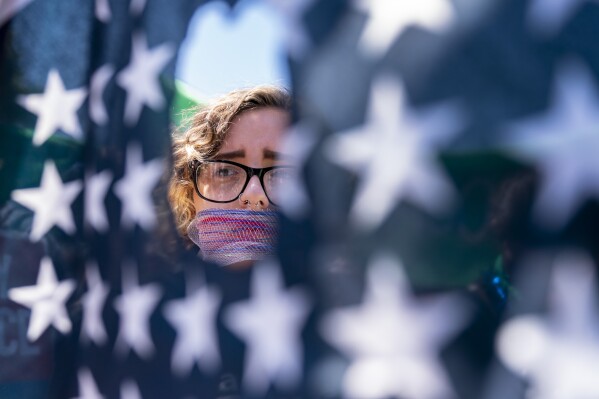 FILE - Emma Rousseau of Oakland, N.J., her mouth bound with a red, white and blue netting, attends a rally on the Fourth of July to protest for abortion rights, at Lafayette Park in front of the White House in Washington, Monday, July 4, 2022. One year ago, the U.S. Supreme Court rescinded a five-decade-old right to abortion, prompting a seismic shift in debates about politics, values, freedom and fairness. (AP Photo/Andrew Harnik, File)